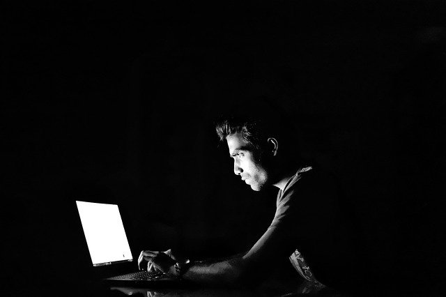 An image of a man sitting in front of a laptop in the dark symbolizing that online privacy is the new black.