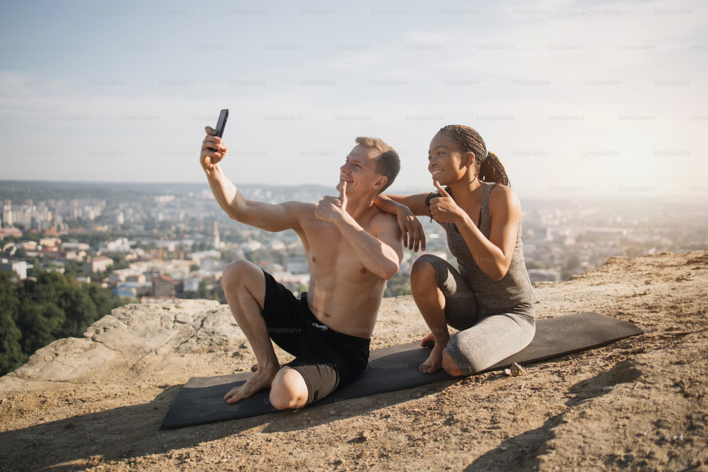 couple doing yoga on hill side, taking selfie together